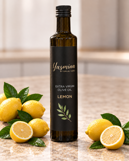 A bottle of Yasmina by Dalal Kani lemon extra virgin olive oil stands on a kitchen counter surrounded by fresh lemons, green leaves, and a softly blurred kitchen background.