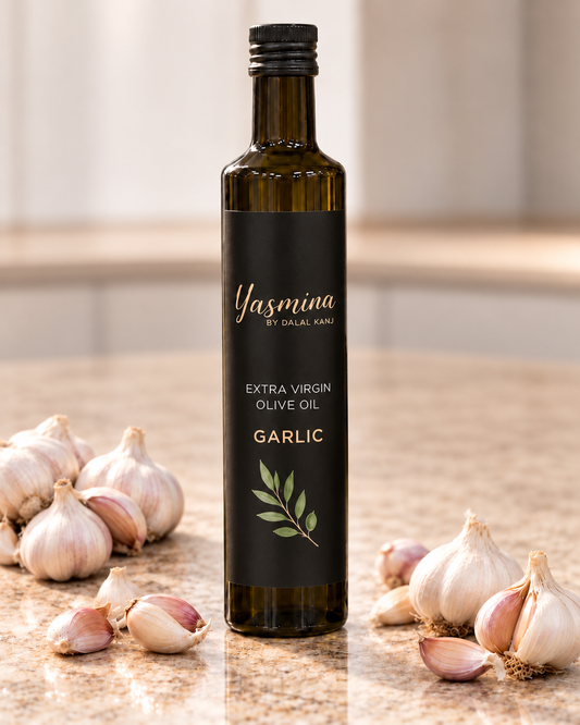 Yasmina by Dalal Kanj certified organic extra virgin olive oil with garlic, dark glass bottle surrounded by fresh garlic bulbs and olive branch